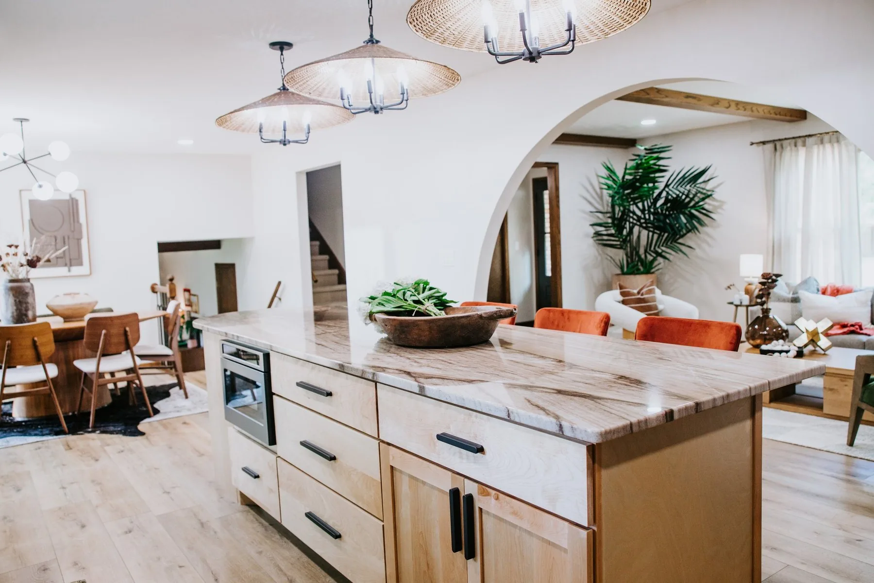 A remodeled kitchen and living space by Pride Built Homes with an arched opening and stone island